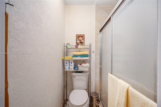 bathroom with a shower with door and toilet