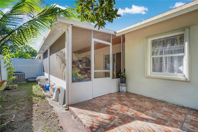 view of side of property featuring a sunroom, central AC, and a patio area