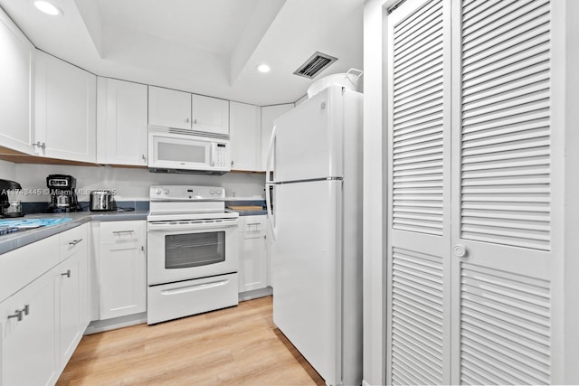 kitchen featuring white cabinetry, light wood-type flooring, white appliances, and a tray ceiling