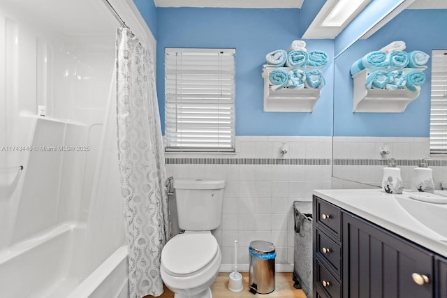 full bathroom with tile walls, vanity, toilet, and shower / bath combo with shower curtain