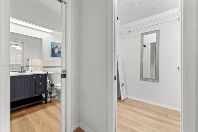 bathroom featuring wood-type flooring, vanity, a textured ceiling, and toilet