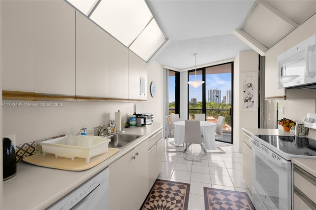 20281 E Country Club Dr Unit 403, Aventura, FL 33180 - kitchen with white appliances, a sink, expansive windows, light countertops, and hanging light fixtures
