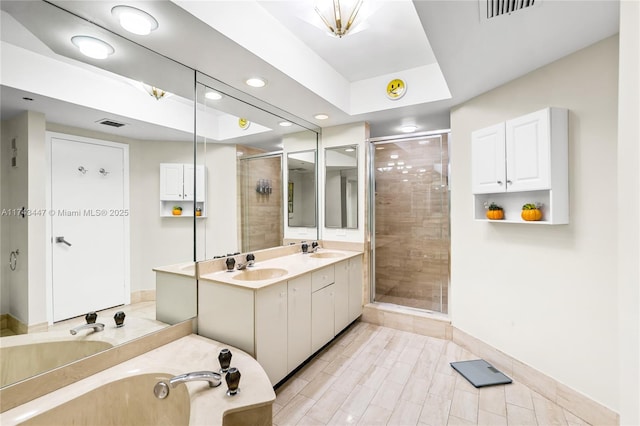 bathroom with vanity, a tray ceiling, and shower with separate bathtub