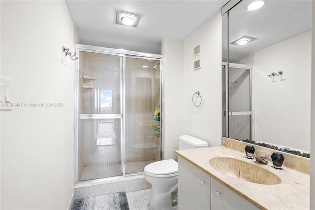 bathroom featuring vanity, a shower with shower door, and toilet