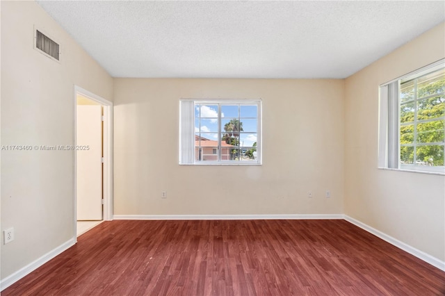 unfurnished room with hardwood / wood-style flooring and a textured ceiling