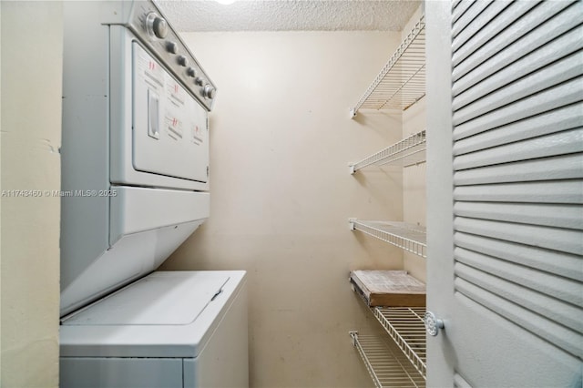 laundry room with a textured ceiling and stacked washing maching and dryer