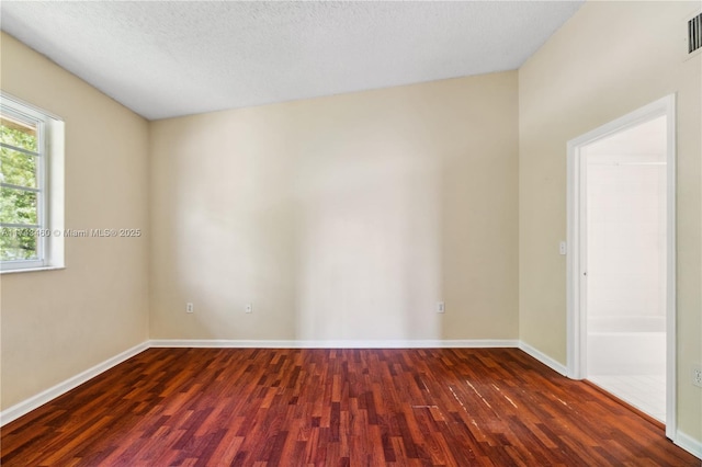 unfurnished room with dark hardwood / wood-style flooring and a textured ceiling