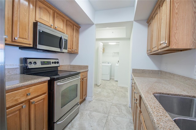 kitchen featuring light stone counters, stainless steel appliances, and sink