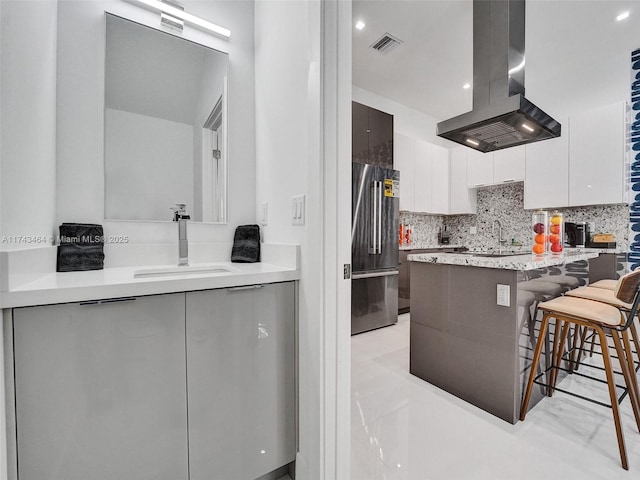 kitchen featuring a kitchen bar, sink, white cabinetry, high end refrigerator, and island exhaust hood