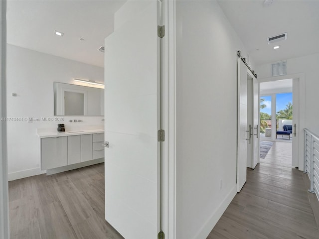 hall with a barn door and light wood-type flooring