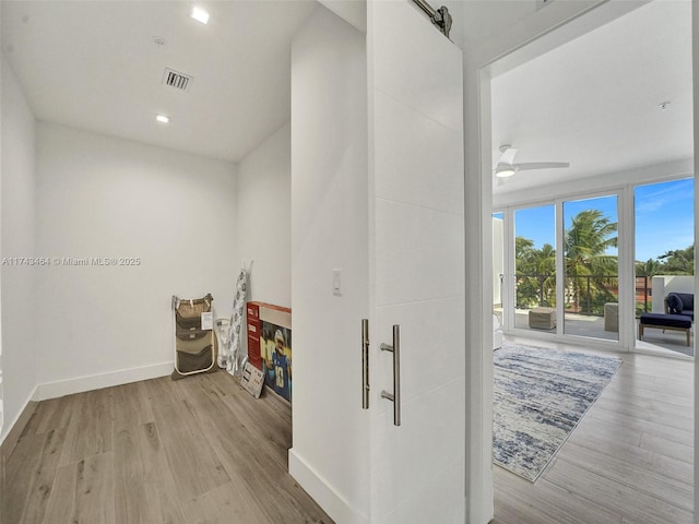 hallway with a barn door and light wood-type flooring