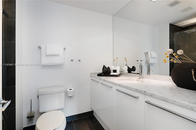 bathroom with tile patterned floors, vanity, toilet, and a shower