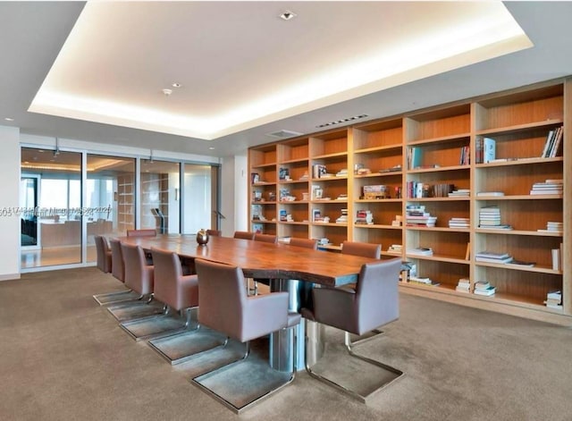 carpeted dining space featuring a raised ceiling