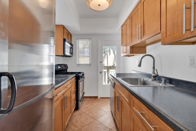 kitchen with sink, a tray ceiling, light tile patterned floors, and appliances with stainless steel finishes