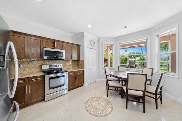 kitchen featuring stainless steel appliances, light stone counters, ornamental molding, decorative backsplash, and decorative light fixtures