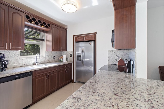 kitchen with appliances with stainless steel finishes, sink, backsplash, light tile patterned floors, and light stone countertops