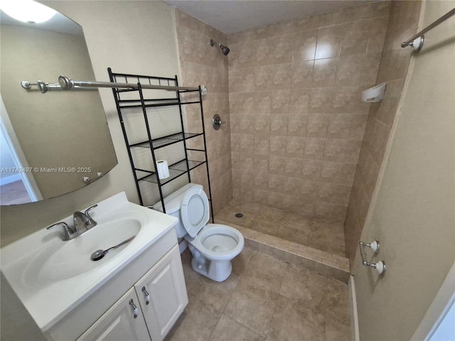 bathroom featuring tile patterned floors, vanity, toilet, and a tile shower