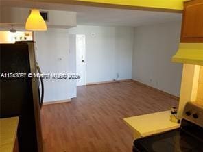 kitchen with black fridge, hardwood / wood-style floors, and stainless steel electric range