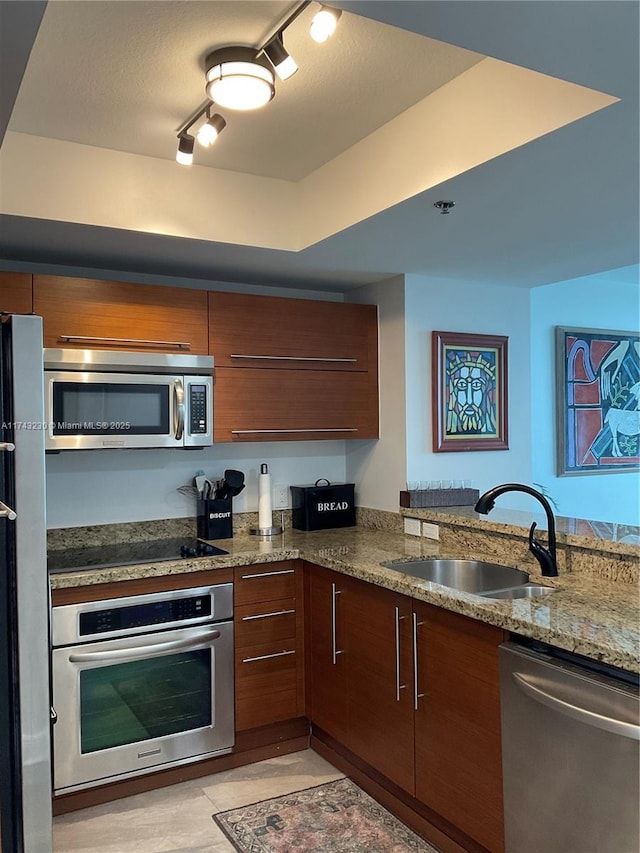 kitchen featuring sink, kitchen peninsula, stone counters, and appliances with stainless steel finishes