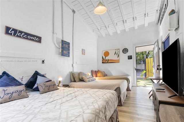 bedroom featuring access to exterior, high vaulted ceiling, wooden ceiling, light wood-type flooring, and beam ceiling