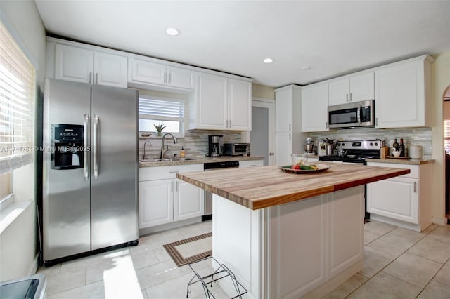 kitchen with sink, a kitchen island, white cabinets, and appliances with stainless steel finishes