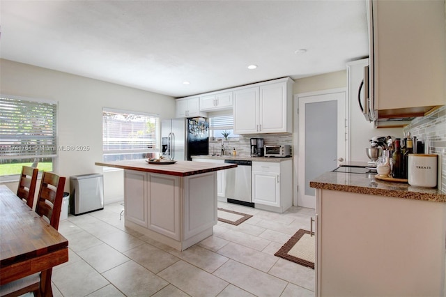 kitchen featuring backsplash, stainless steel appliances, a center island, and white cabinets