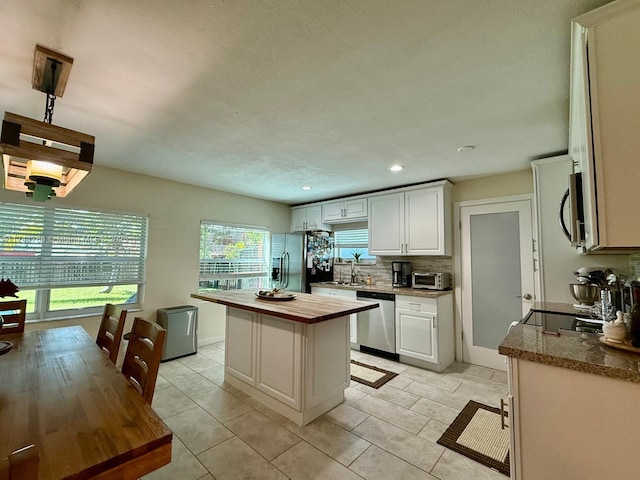 kitchen with sink, white cabinets, backsplash, a center island, and stainless steel appliances