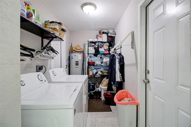 washroom featuring a textured ceiling, electric water heater, washer and dryer, and light tile patterned floors