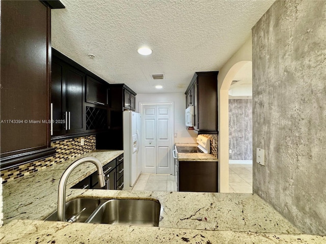 kitchen with sink, light stone counters, light tile patterned floors, white appliances, and backsplash