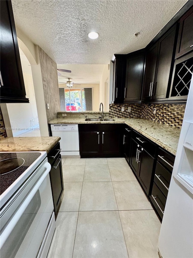 kitchen featuring light stone counters, sink, white appliances, and light tile patterned floors