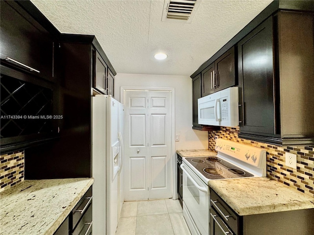 kitchen featuring light stone counters, white appliances, light tile patterned flooring, and tasteful backsplash