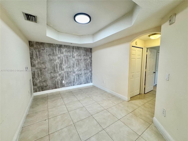 tiled empty room with a raised ceiling