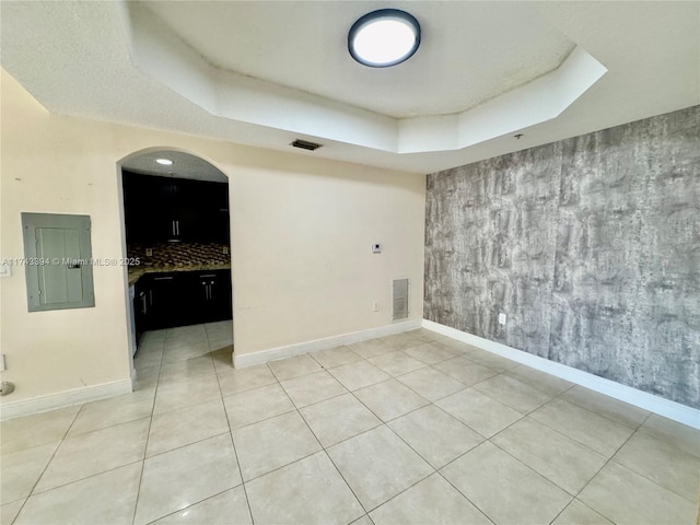 unfurnished room featuring tile patterned flooring, a tray ceiling, and electric panel