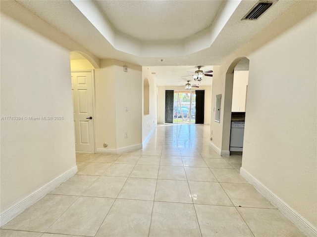 hallway with light tile patterned floors and a tray ceiling