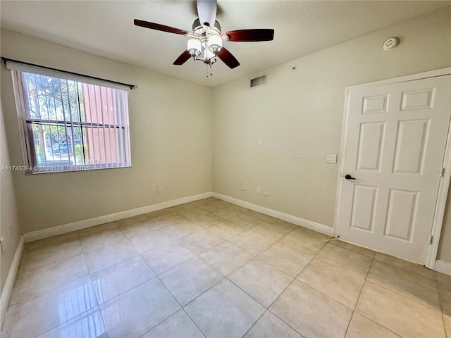 empty room with light tile patterned flooring, a textured ceiling, and ceiling fan