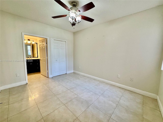 unfurnished bedroom featuring light tile patterned floors, a closet, ceiling fan, and ensuite bathroom