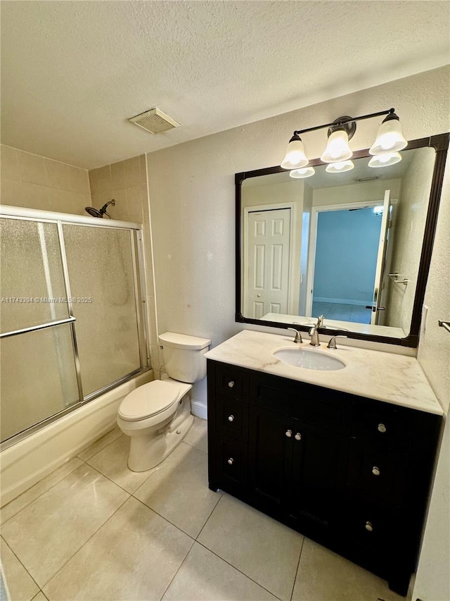 full bathroom featuring shower / bath combination with glass door, vanity, toilet, tile patterned floors, and a textured ceiling