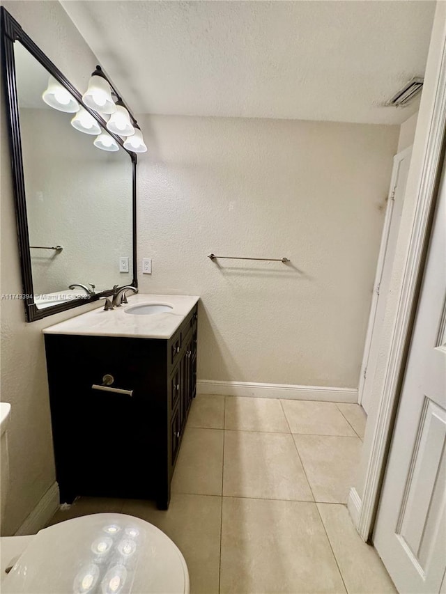 bathroom with tile patterned flooring, vanity, a textured ceiling, and toilet