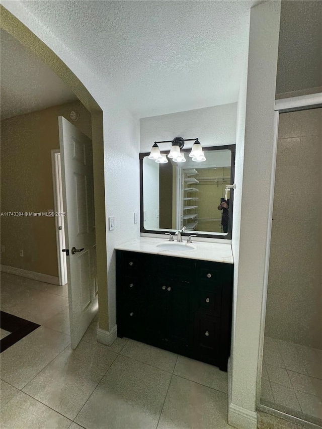 bathroom with tile patterned flooring, vanity, a shower, and a textured ceiling