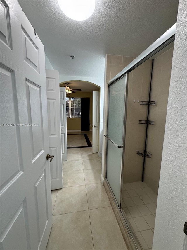 bathroom with tile patterned flooring, an enclosed shower, a textured ceiling, and ceiling fan