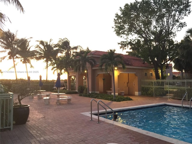 pool at dusk featuring a patio area