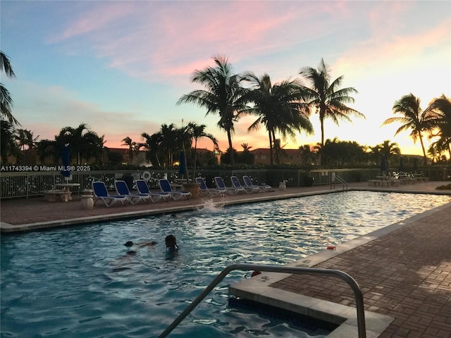 pool at dusk featuring a patio