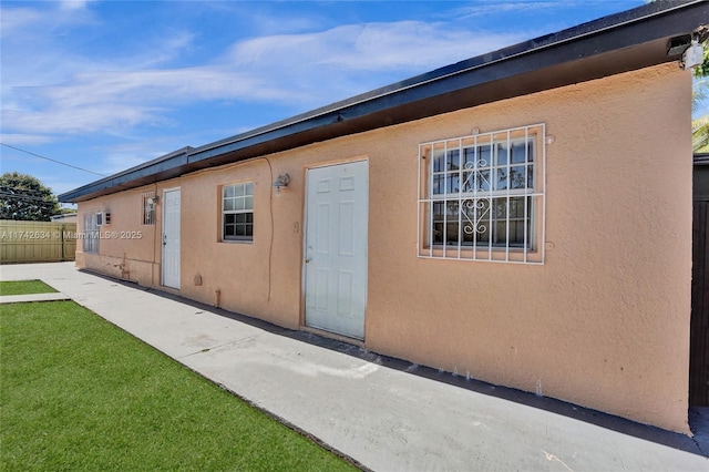 exterior space featuring fence, a lawn, and stucco siding