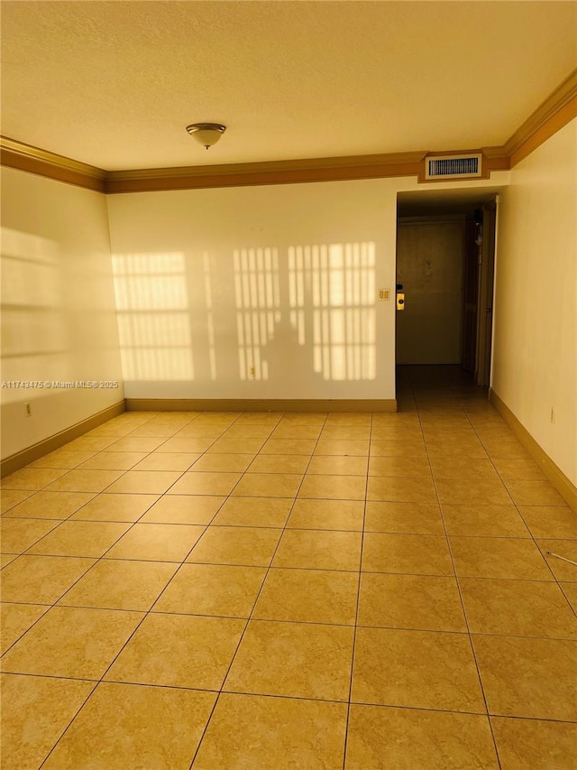 spare room with ornamental molding, a textured ceiling, and light tile patterned floors