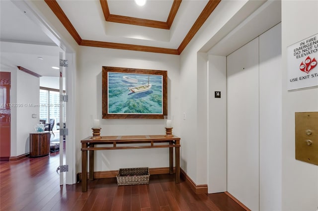 hall featuring a tray ceiling, elevator, baseboards, ornamental molding, and dark wood-style flooring