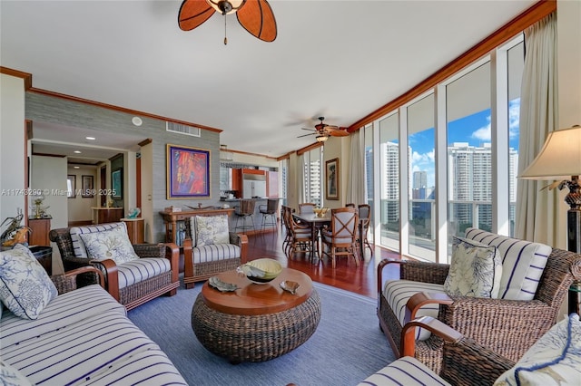 living room featuring a ceiling fan, visible vents, crown molding, and wood finished floors