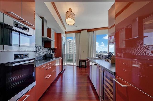 kitchen with double oven, a sink, modern cabinets, and beverage cooler