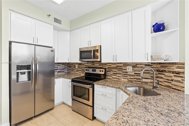 kitchen featuring sink, light stone counters, white cabinets, stainless steel appliances, and backsplash