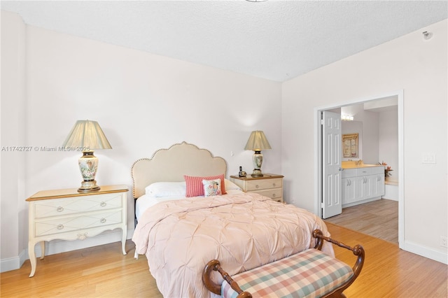 bedroom with light hardwood / wood-style flooring, a textured ceiling, and ensuite bathroom