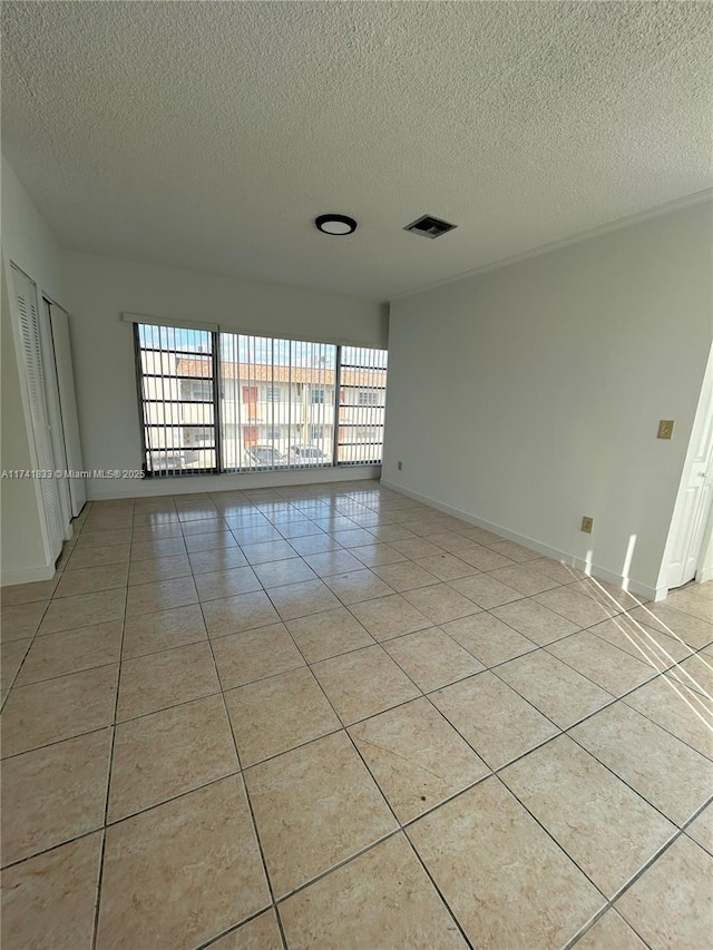 tiled spare room with a textured ceiling